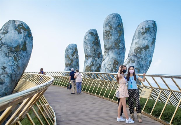 Du khách tham quan chụp ảnh tại cầu Vàng khu du lịch Sun World Ba Na Hills. (Ảnh: TTXVN phát)